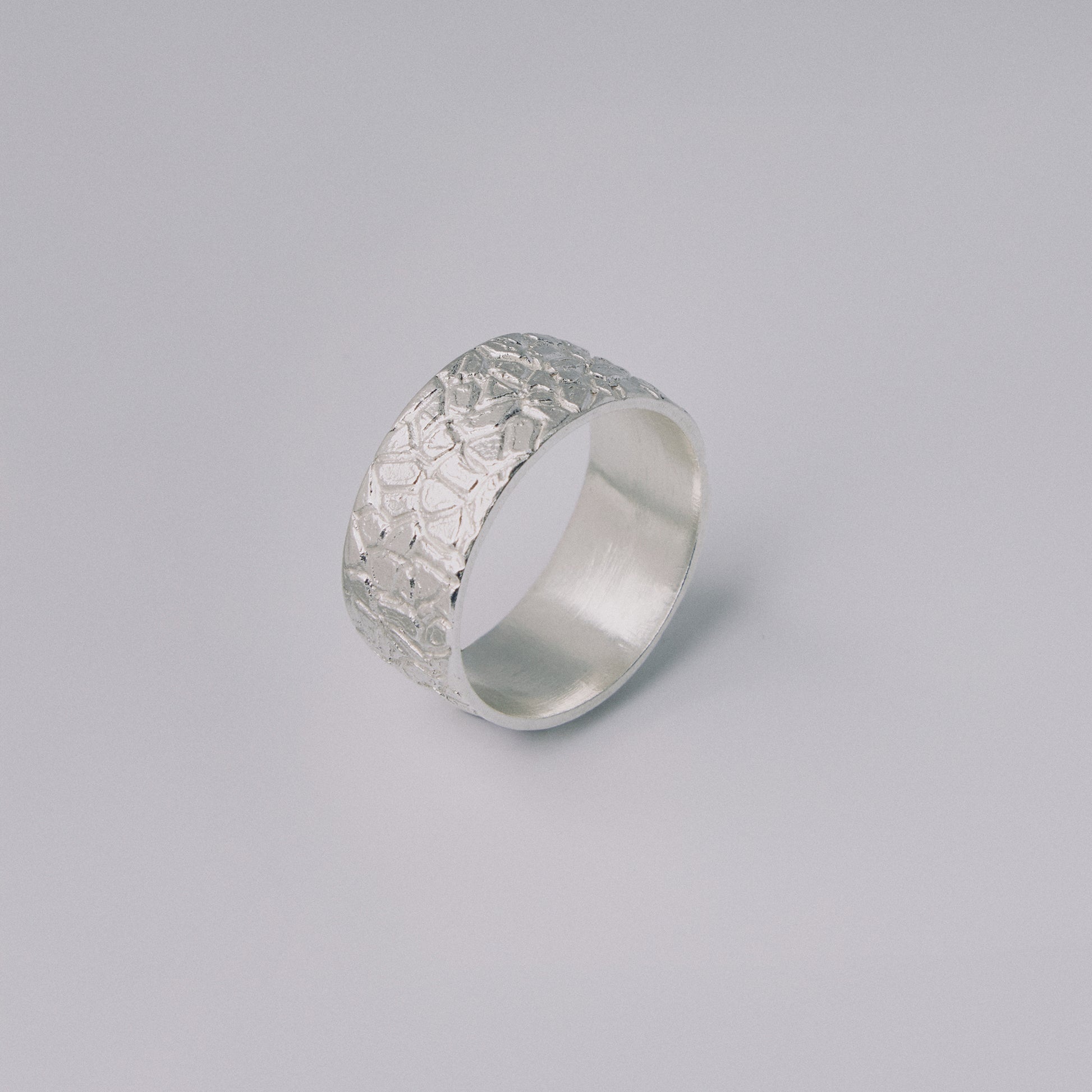 Silver ring with textured surface on a gray background