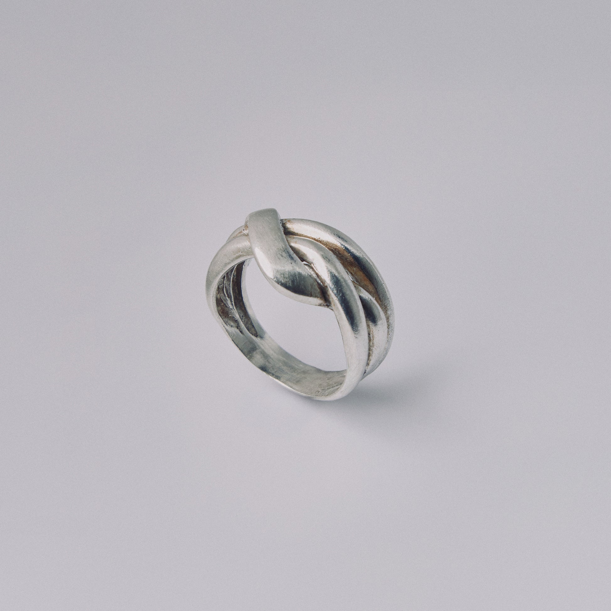 Silver ring with a twisted design on a gray background