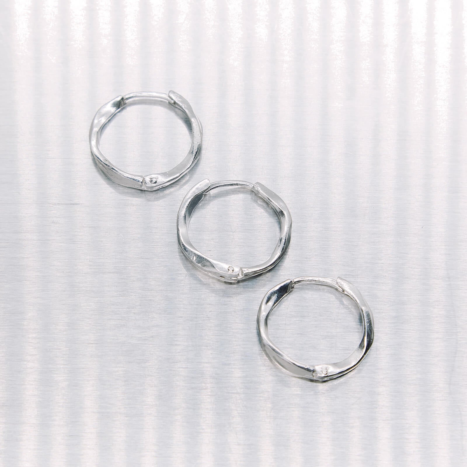 Set of silver hoop earrings on a textured white background