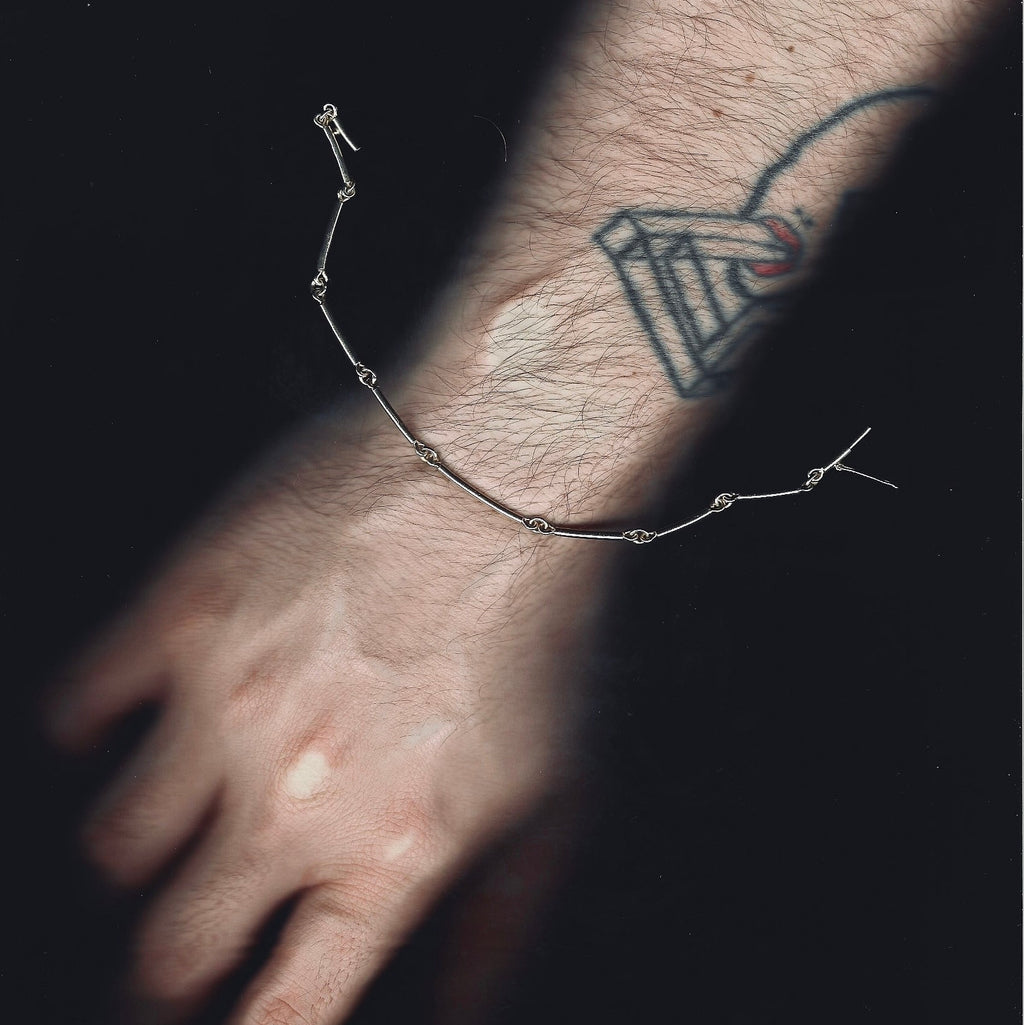 Close-up of a wrist with a bracelet and tattoo on a dark background