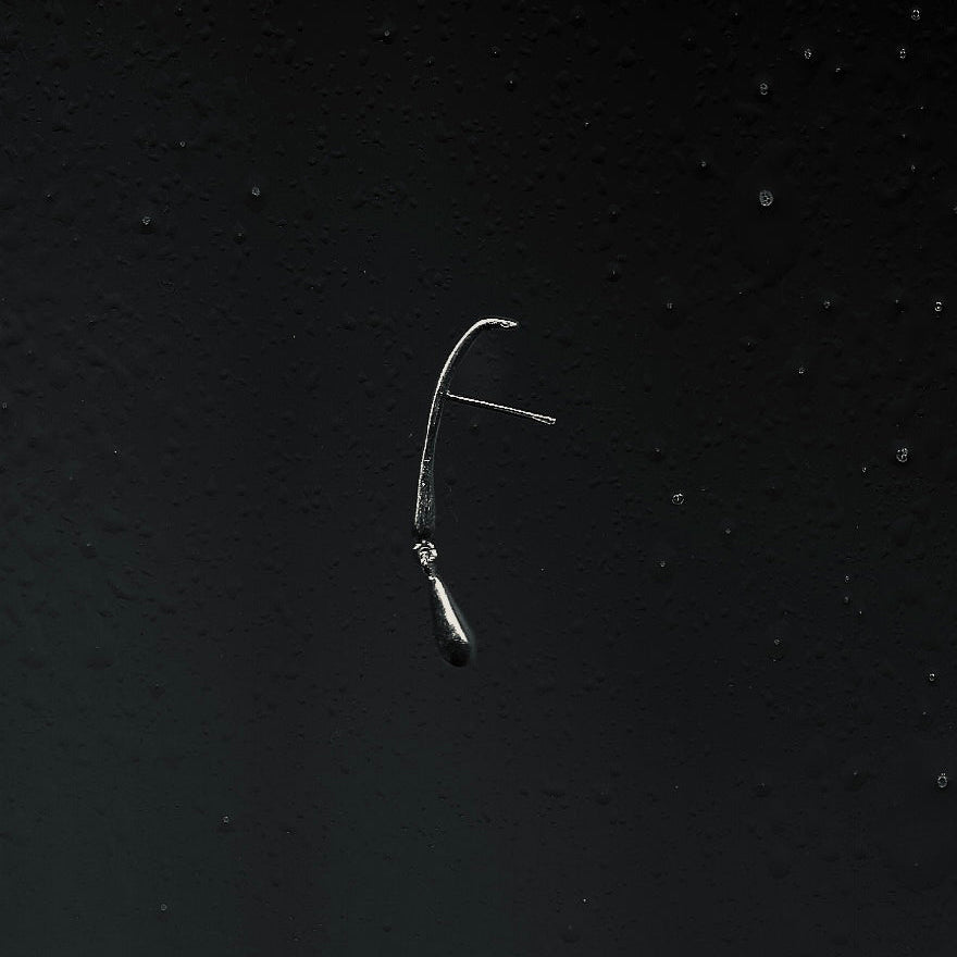 Metallic fishing earring on a textured black background