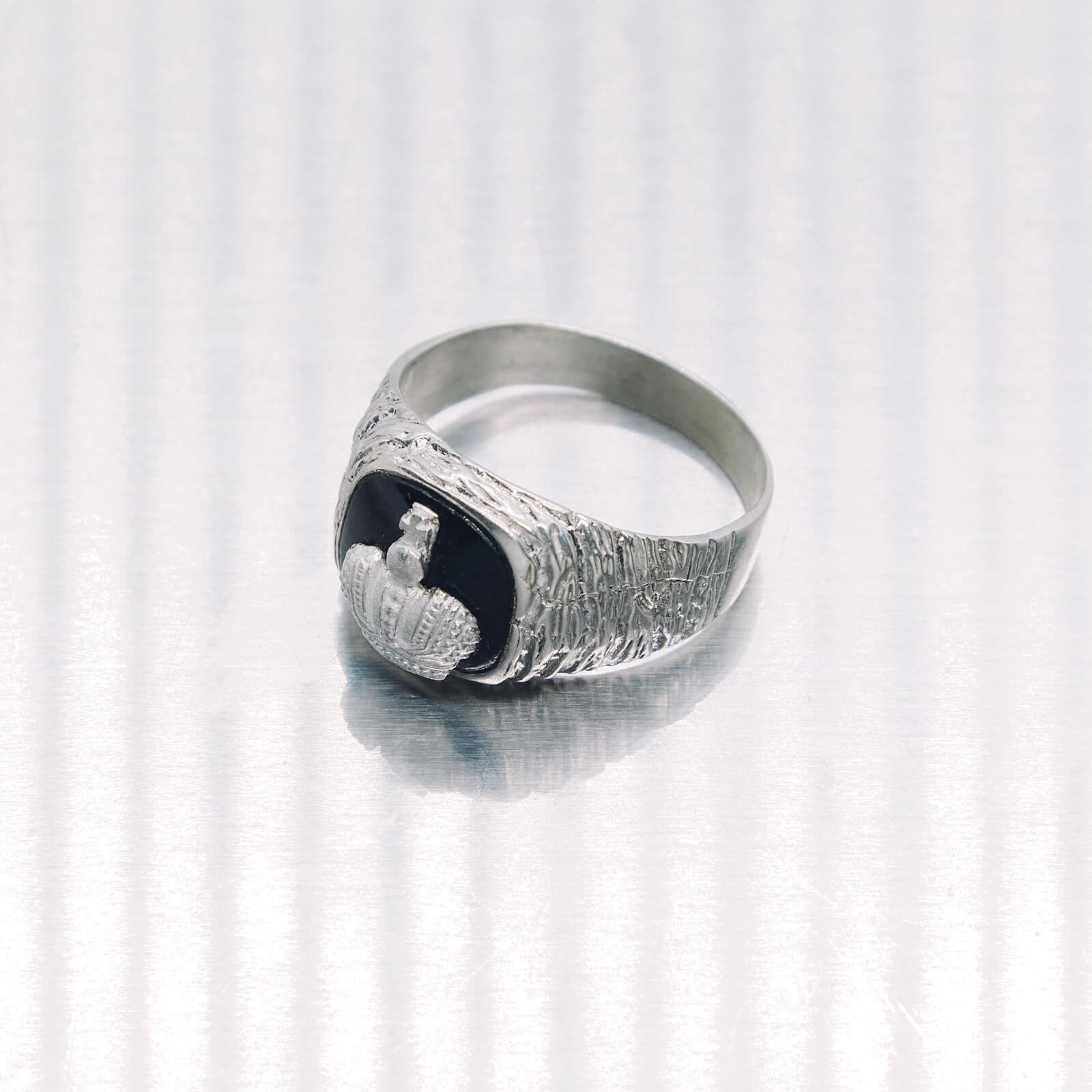 Silver ring with a black stone and engraved design on a white background