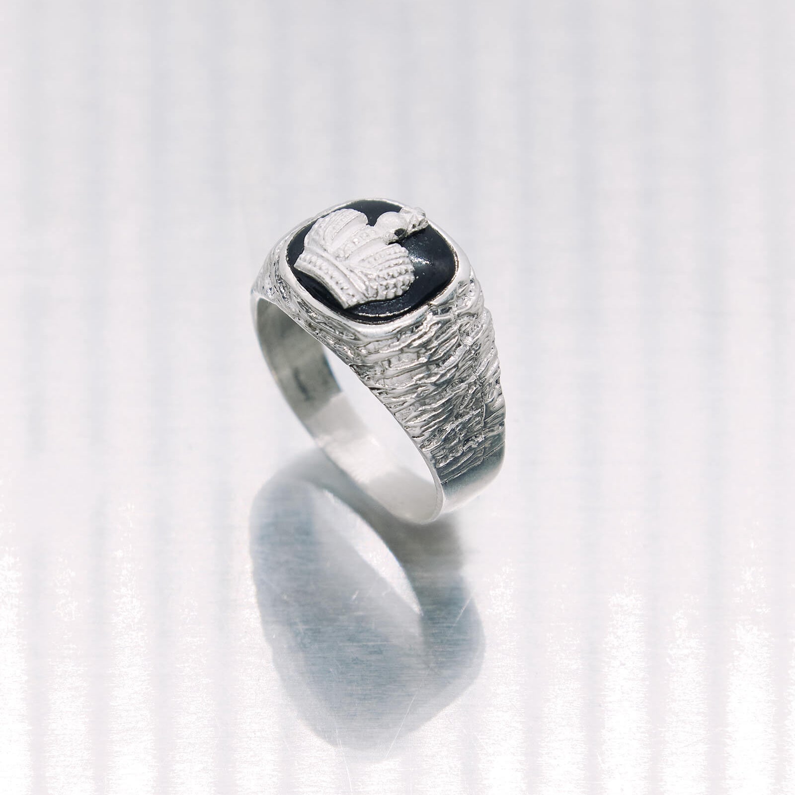 Silver ring with a black stone and bird design on a white background