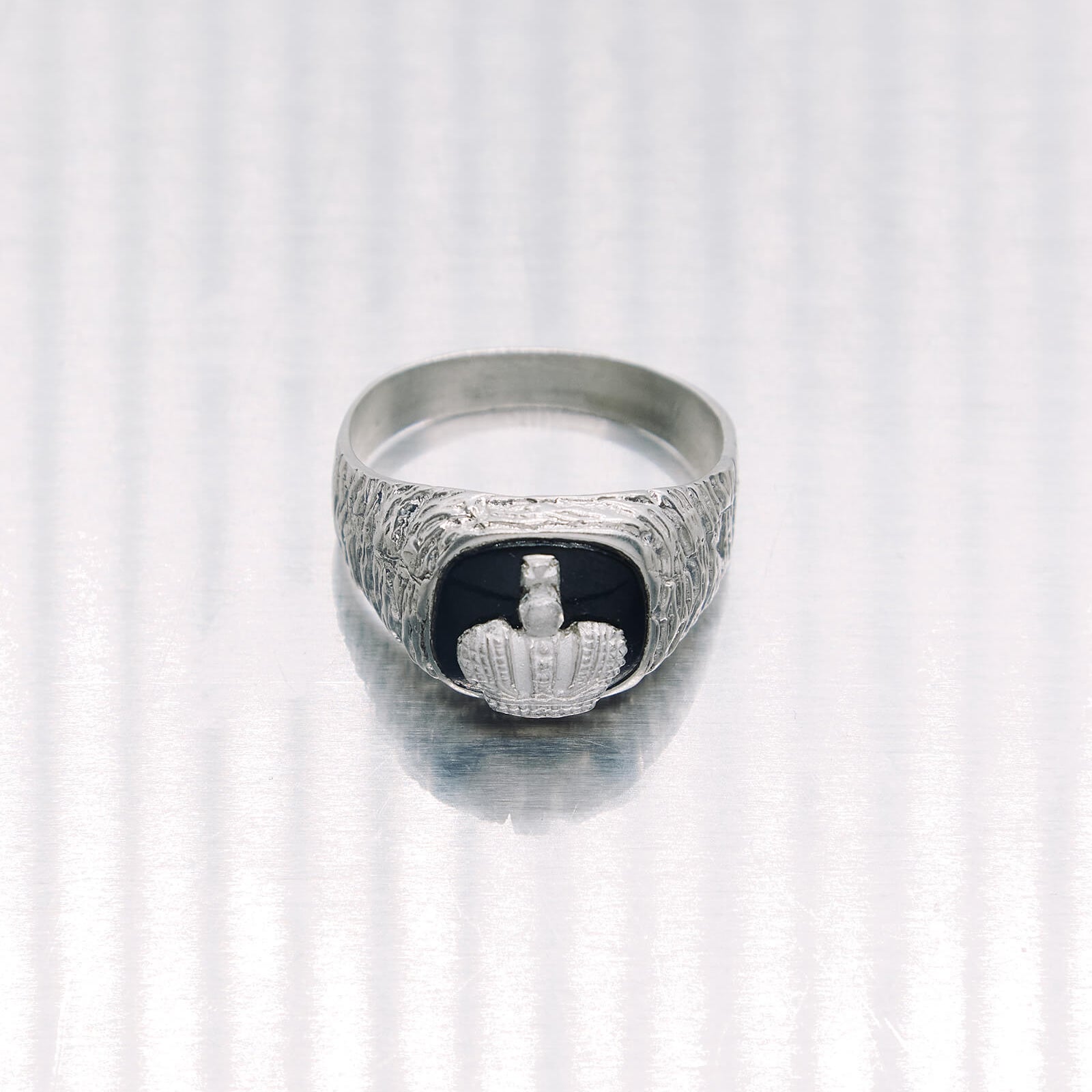 Silver ring with a black stone and engraved design on a white background