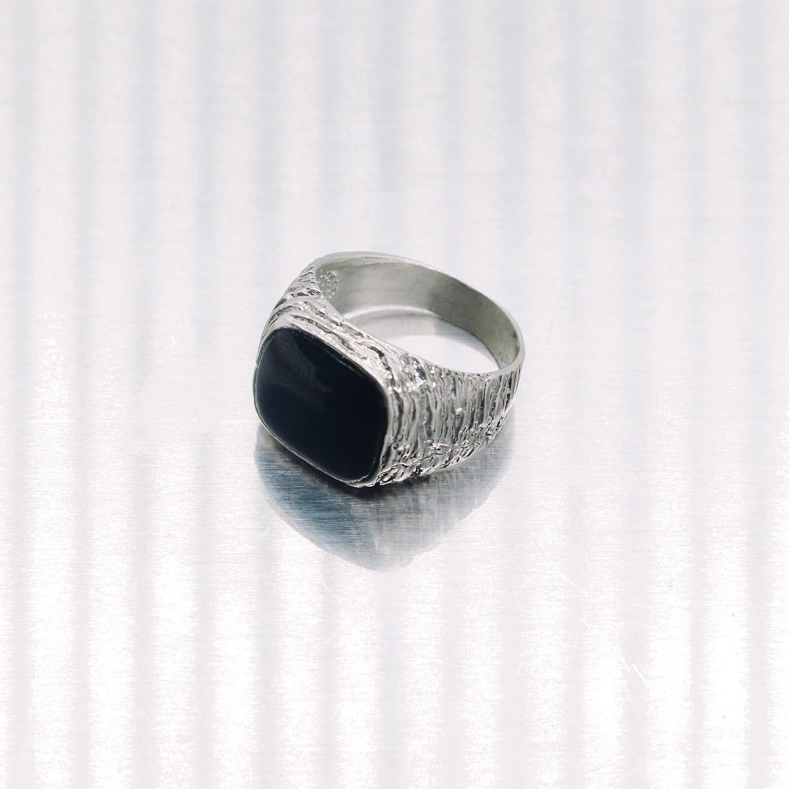 Silver ring with a black stone on a white background