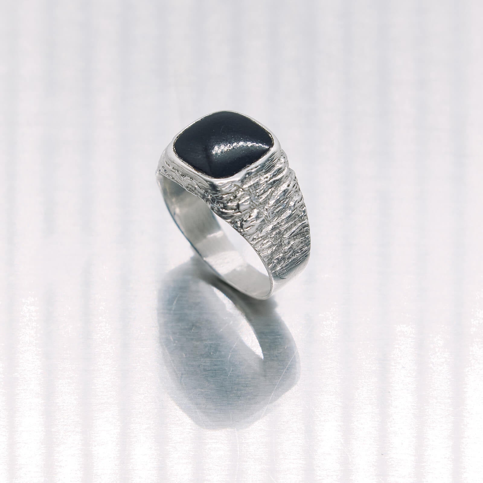 Silver ring with a black stone on a white background