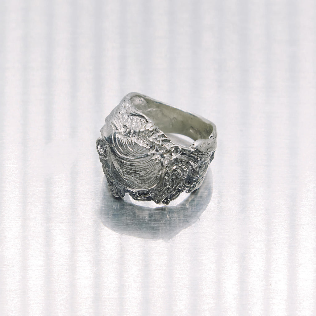 Silver ring with a textured design on a white background