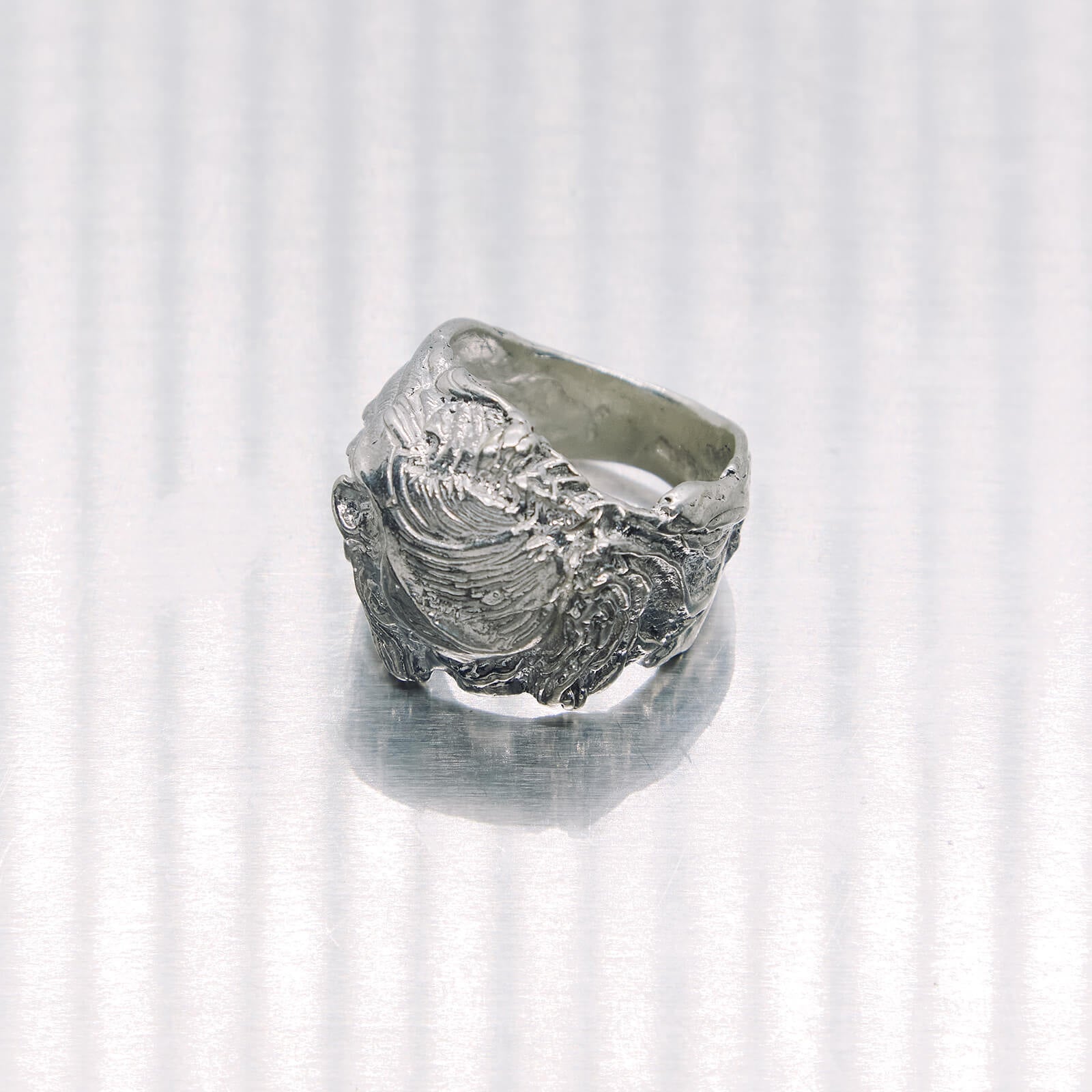 Silver ring with a textured design on a white background