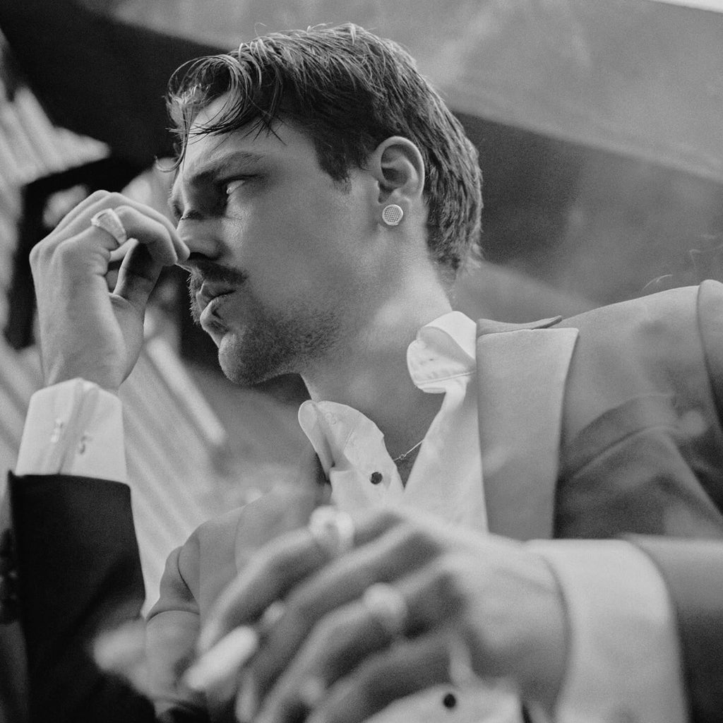 Man in formal attire smoking a cigarette with a blurred background