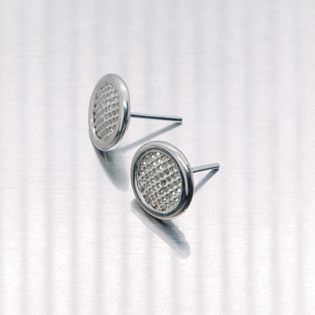 Pair of silver earrings with gemstone-like centers on a white background