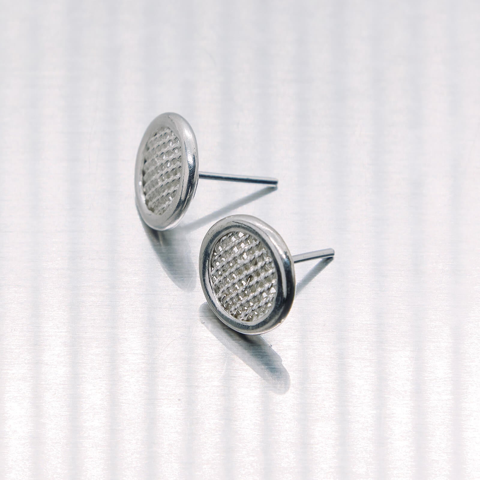 Pair of silver earrings with gemstone-like centers on a white background