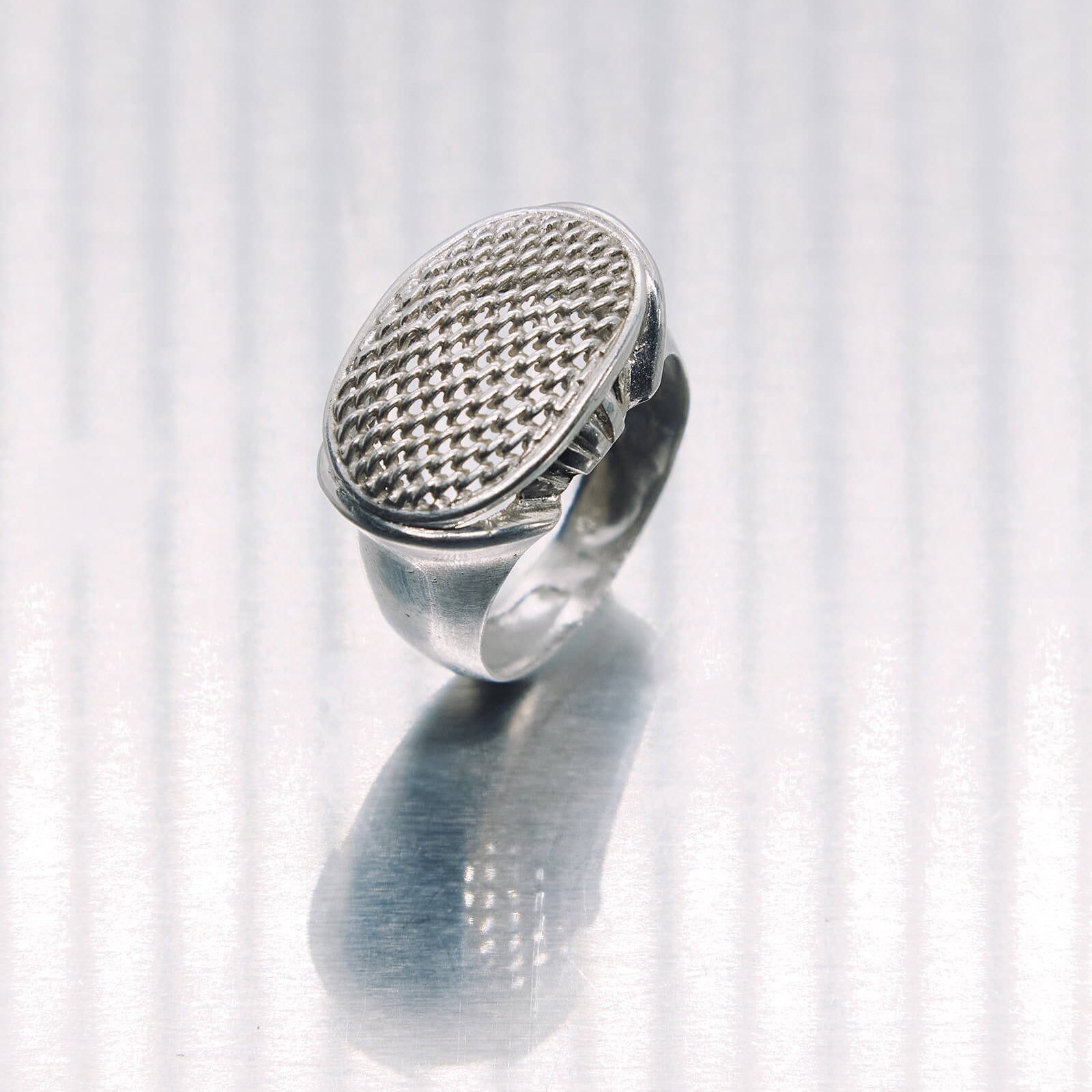 Silver ring with textured design on a white background