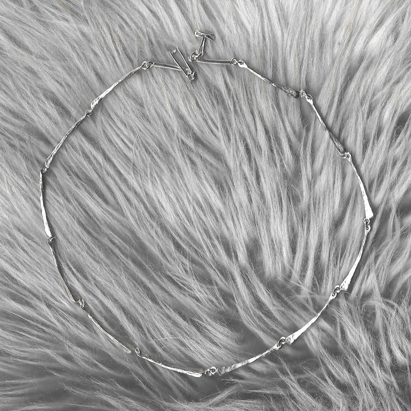 Silver necklace on a fluffy gray surface