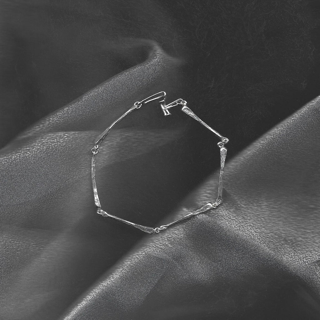 Silver bracelet on a textured black fabric background