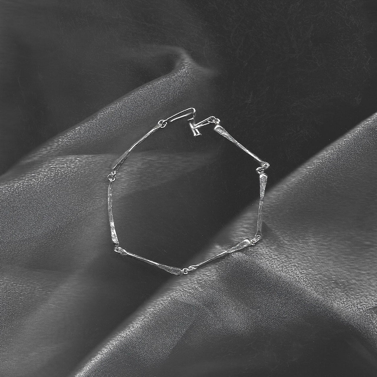 Silver bracelet on a textured black fabric background