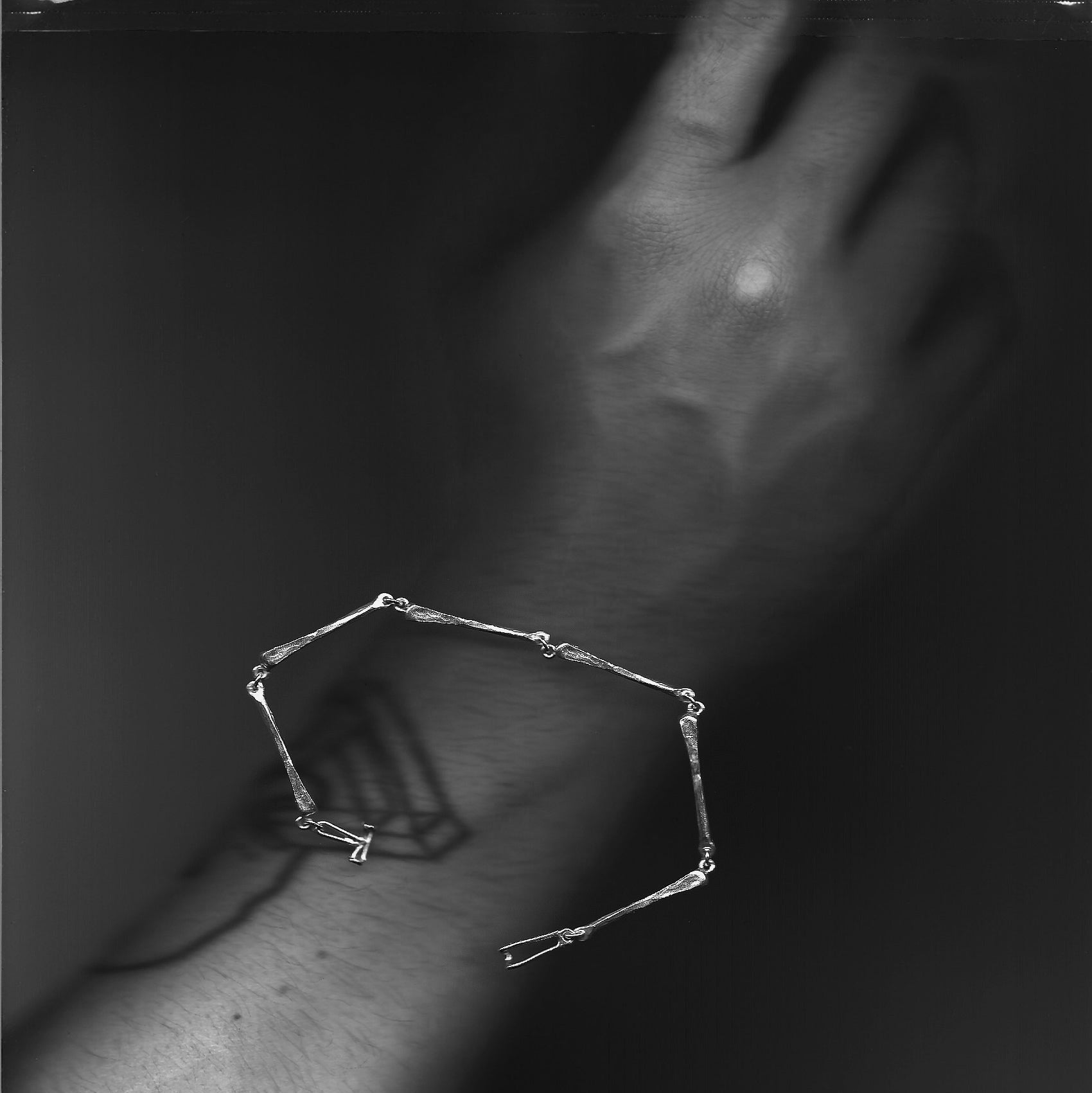 Black and white close-up of a geometric tattoo on a silver bracelet 