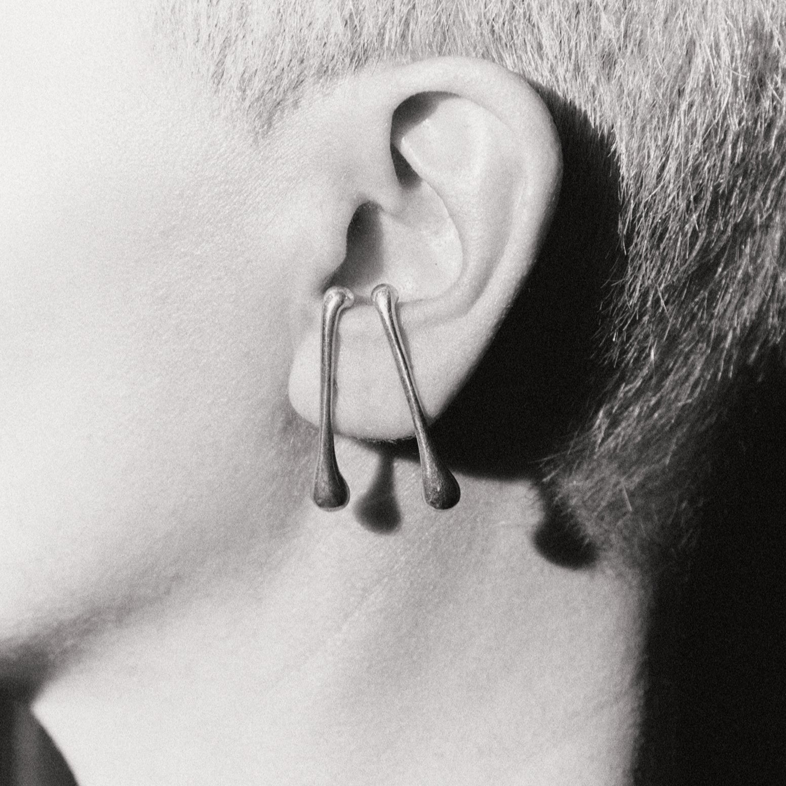 Close-up of an ear wearing a unique earring with a plain background