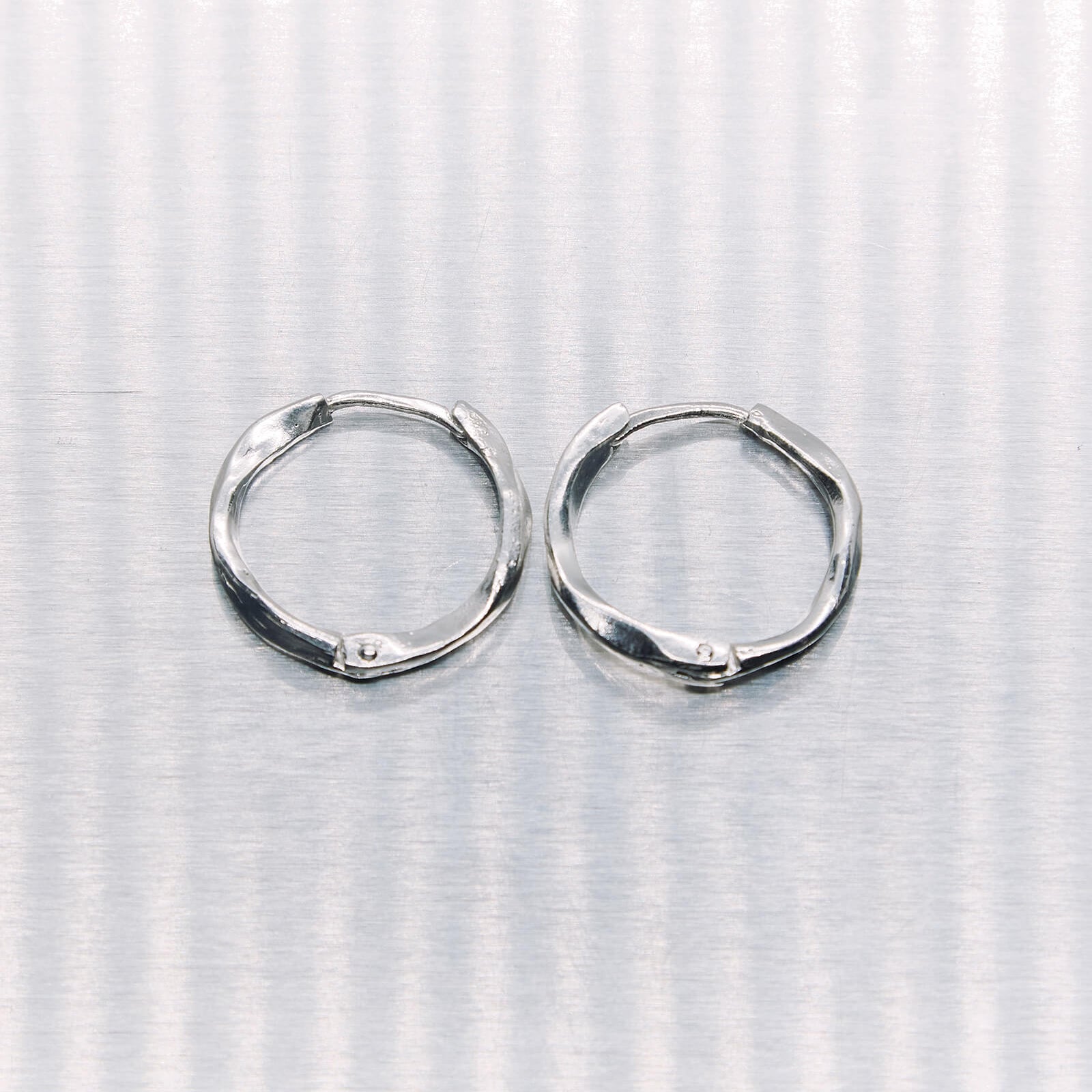 Pair of silver hoop earrings on a textured white background