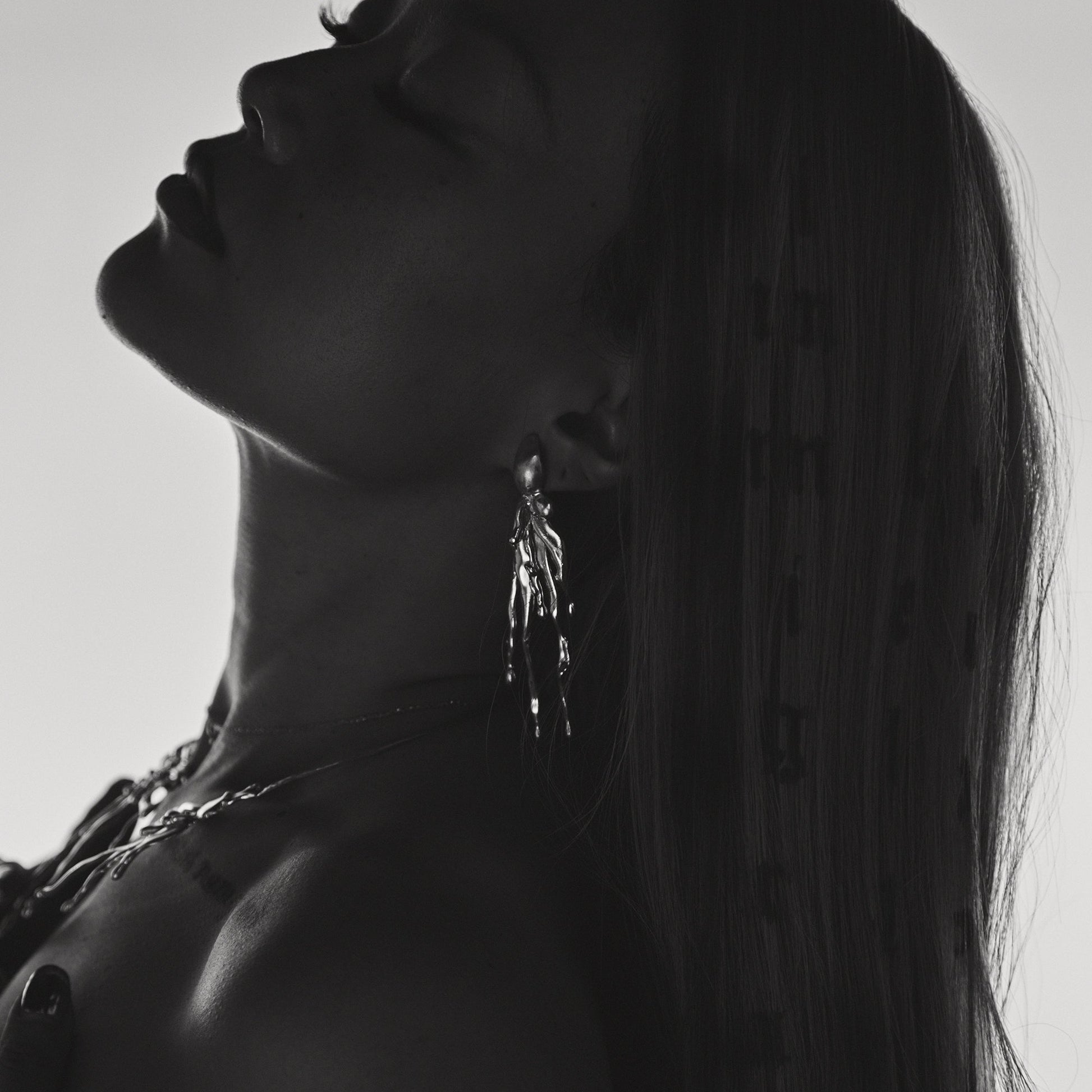 Black and white silhouette of a person wearing earrings with a blurred background
