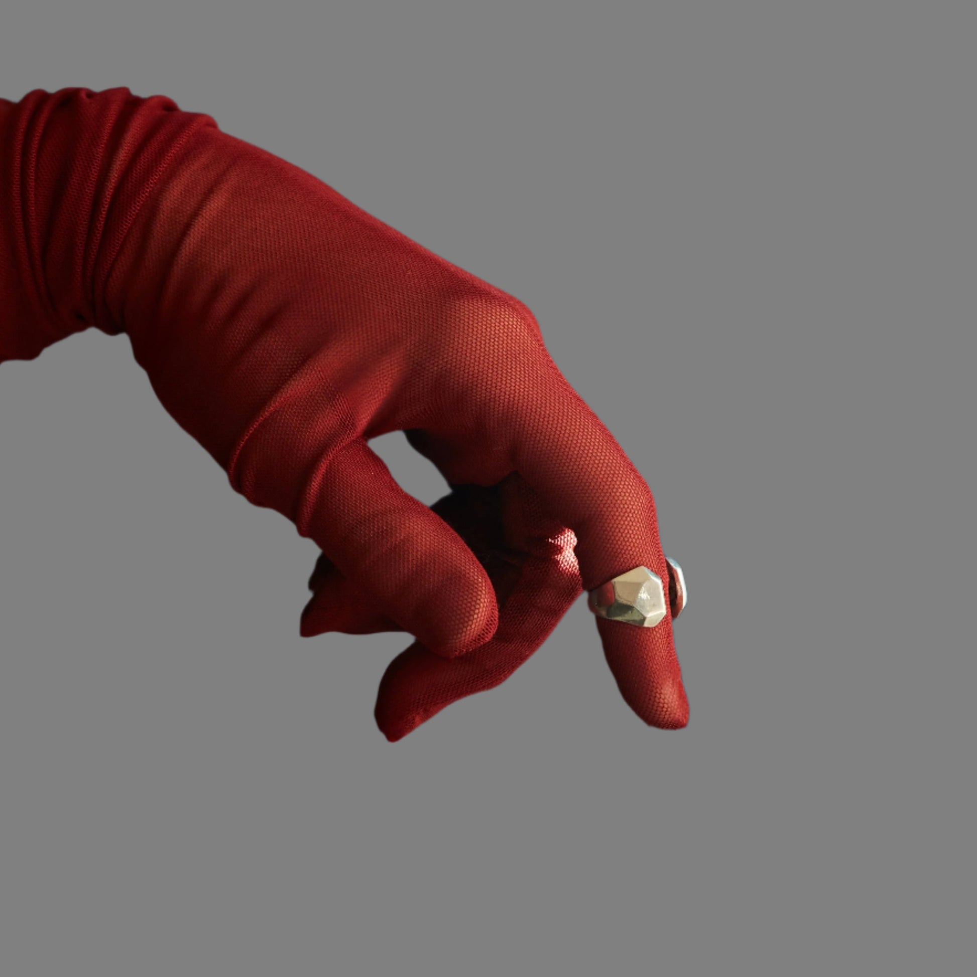 Red-gloved hand with a gold ring on a gray background