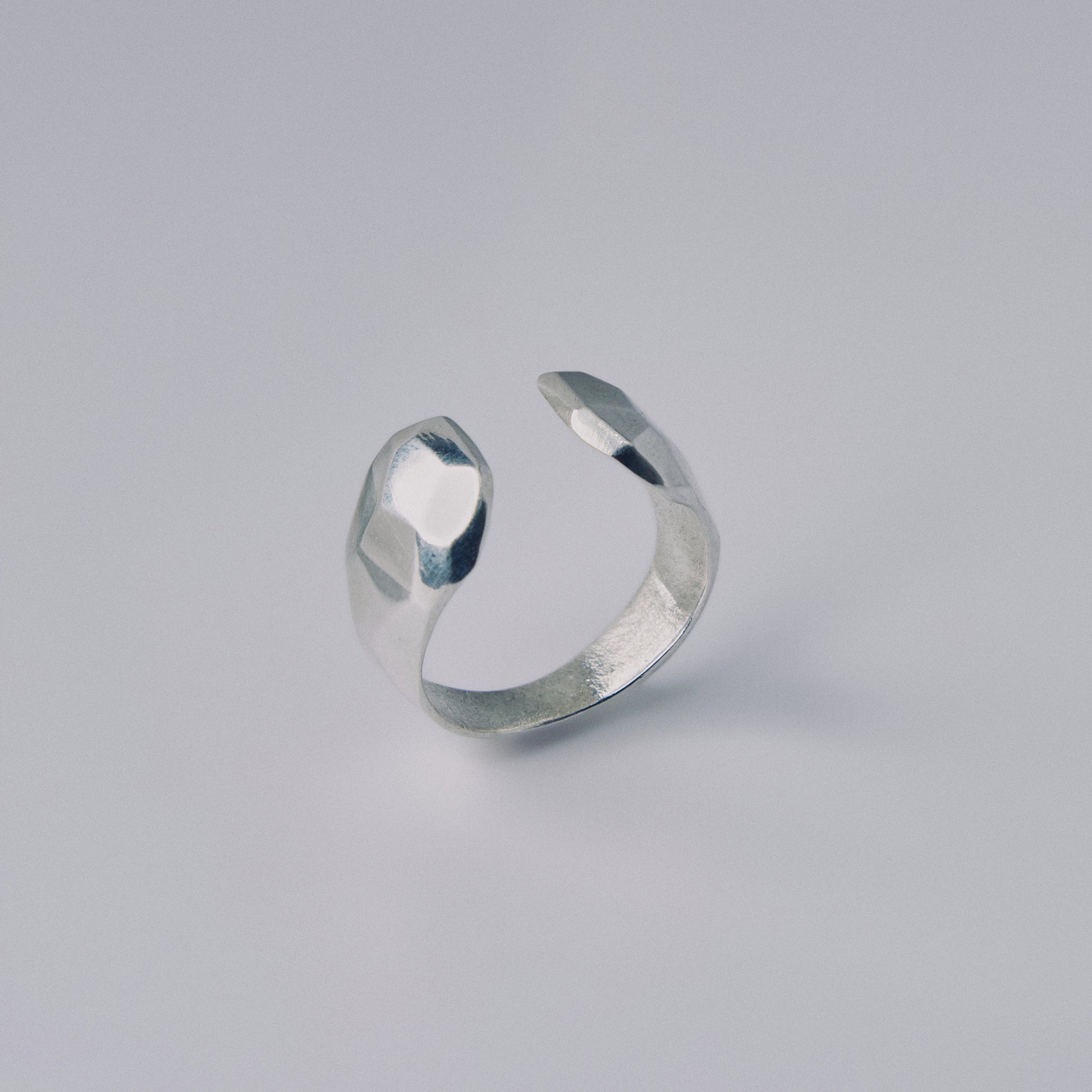 Silver open ring on a light gray background