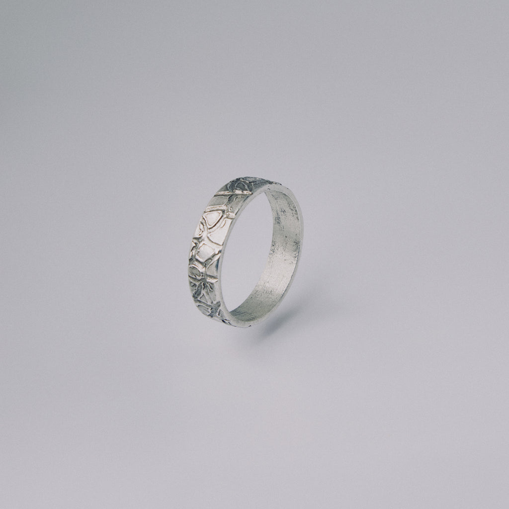 Silver ring with intricate design on a gray background