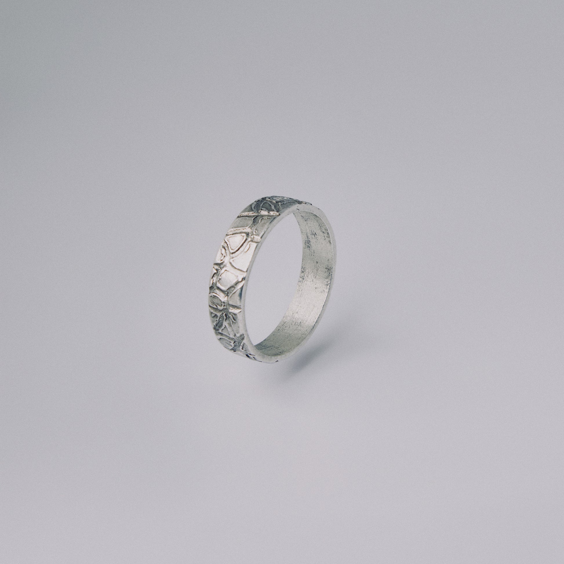 Silver ring with intricate design on a gray background