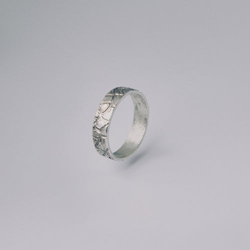 Silver ring with intricate design on a gray background