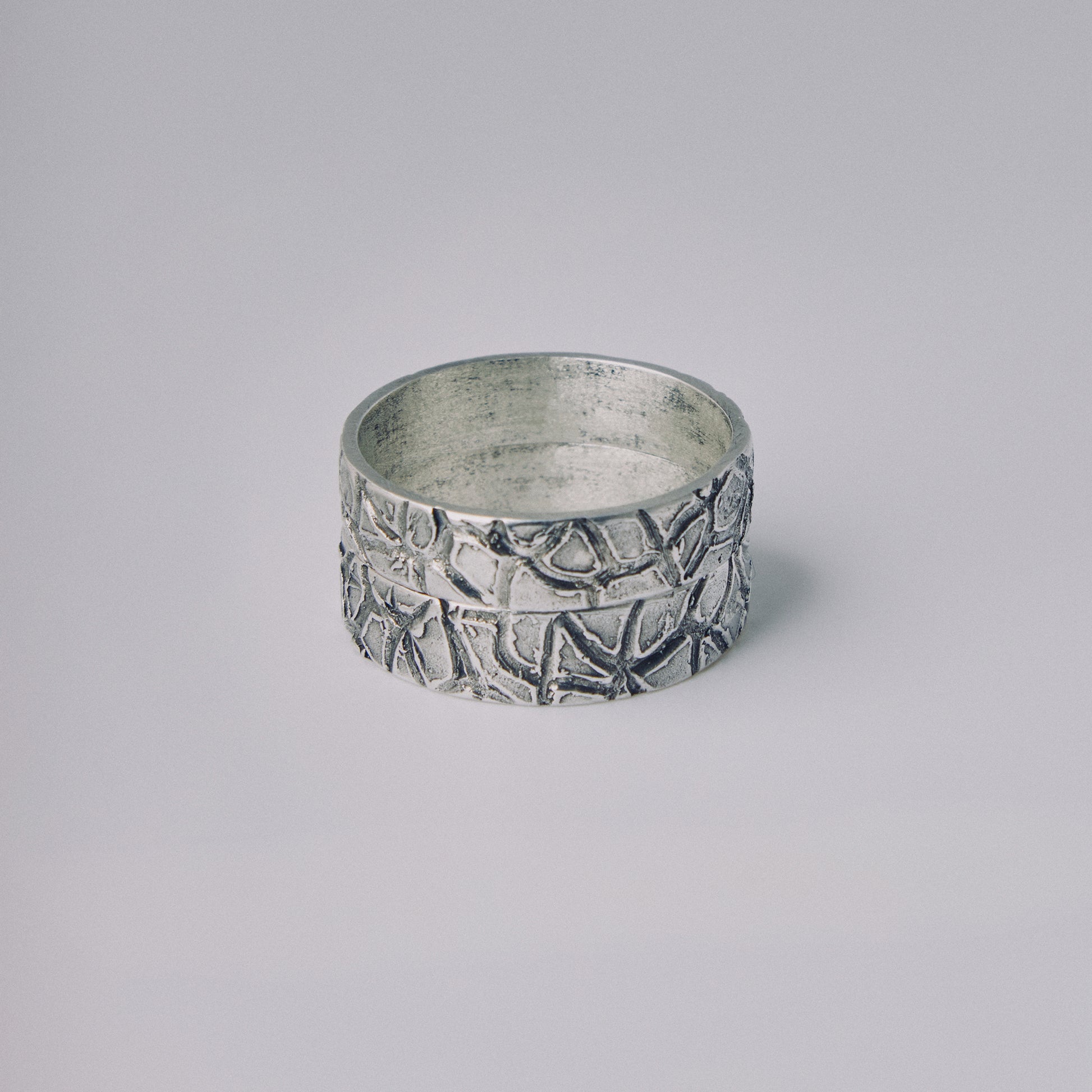 Silver ring with textured design on a gray background