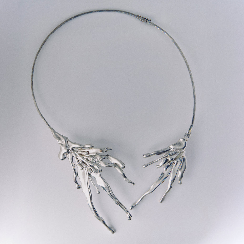 Silver necklace with branch-like design on a light gray background