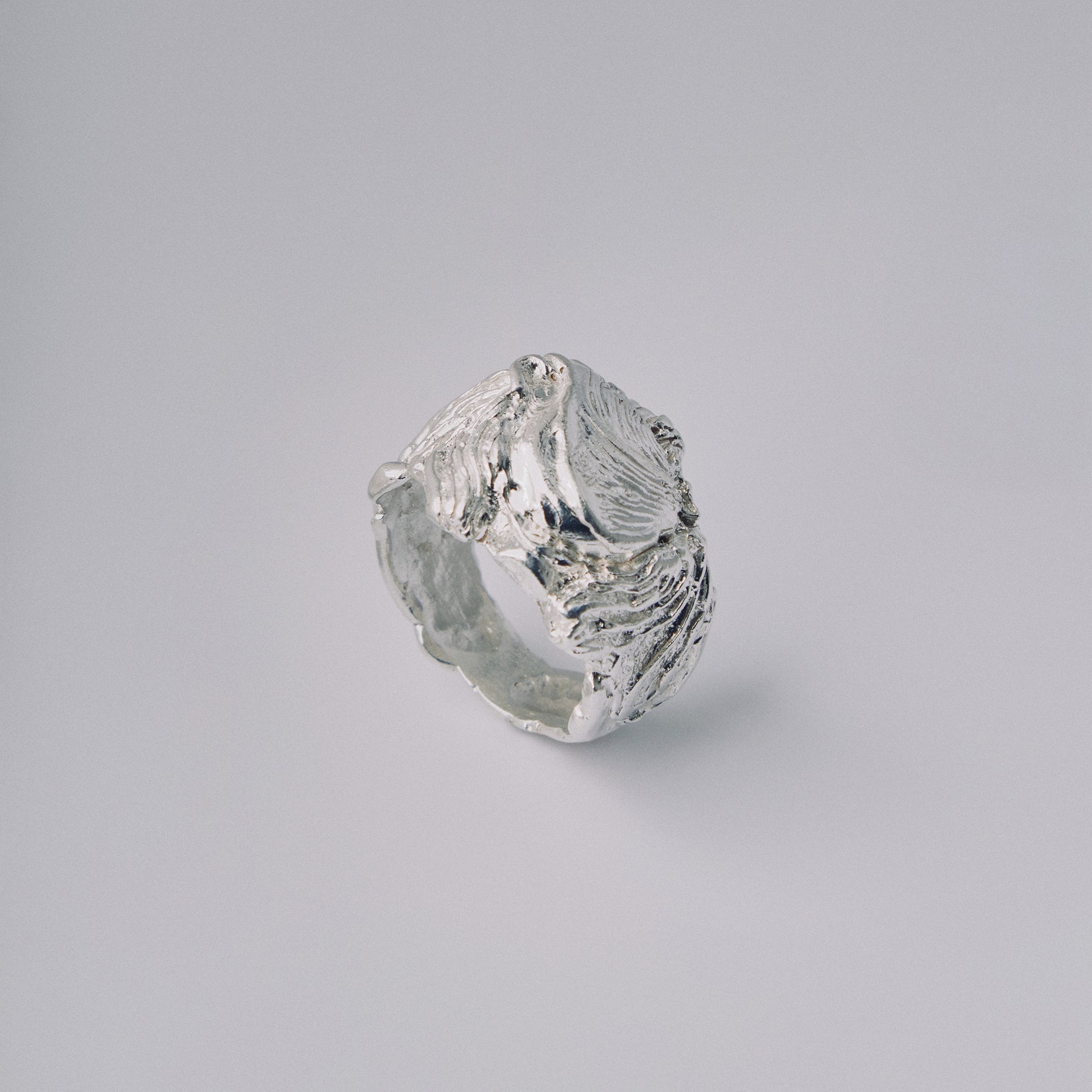 Silver ring with a textured design on a gray background
