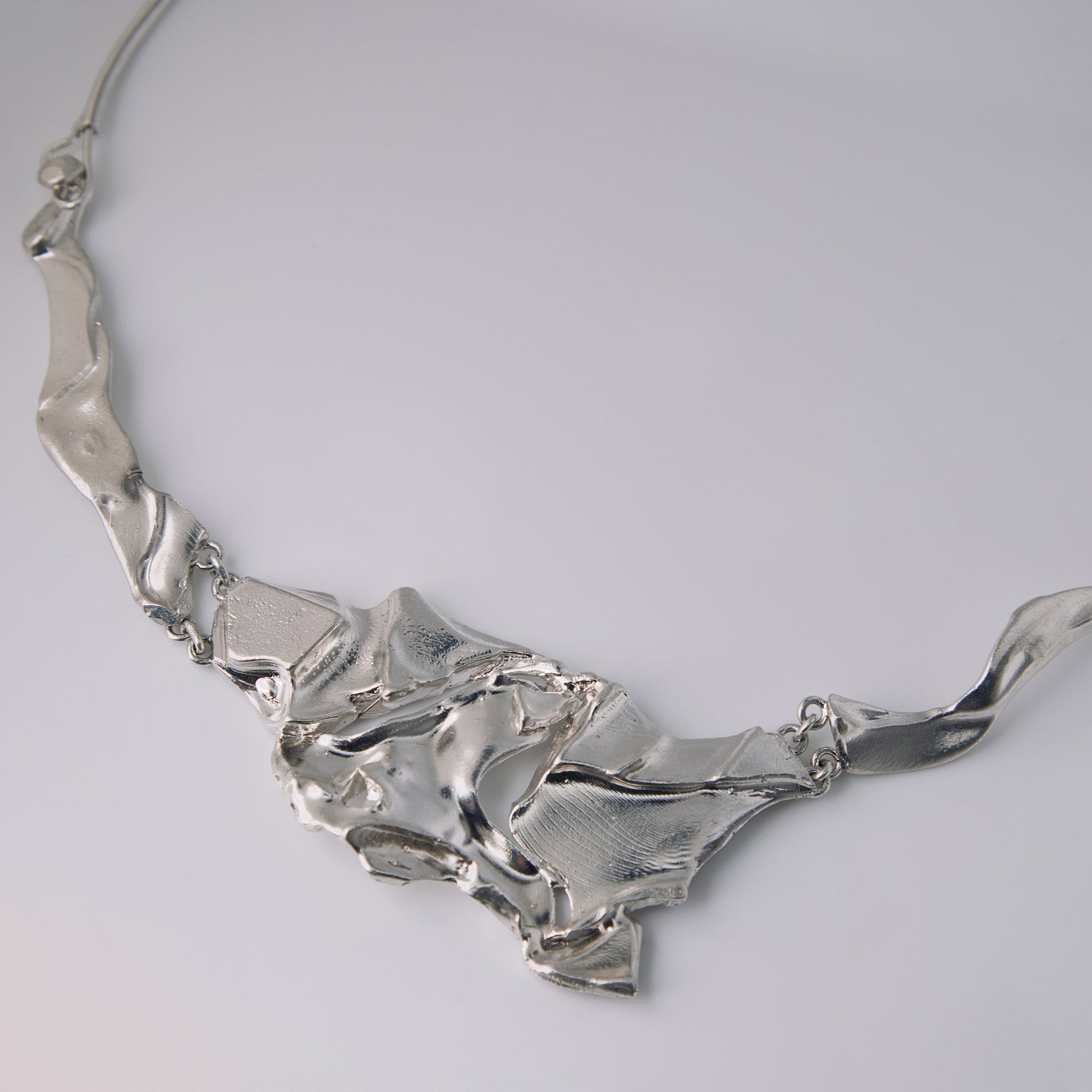Silver necklace on a light gray background