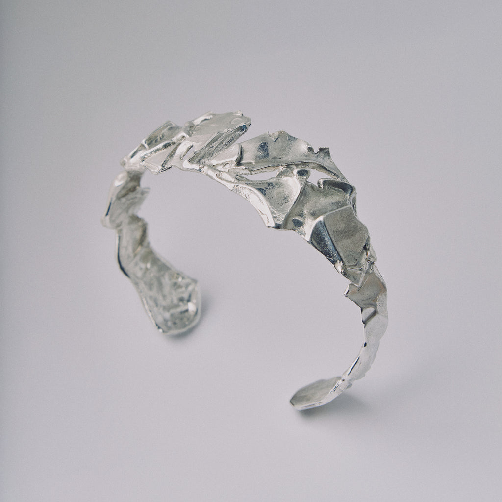 Silver leaf-patterned ring on a light gray background