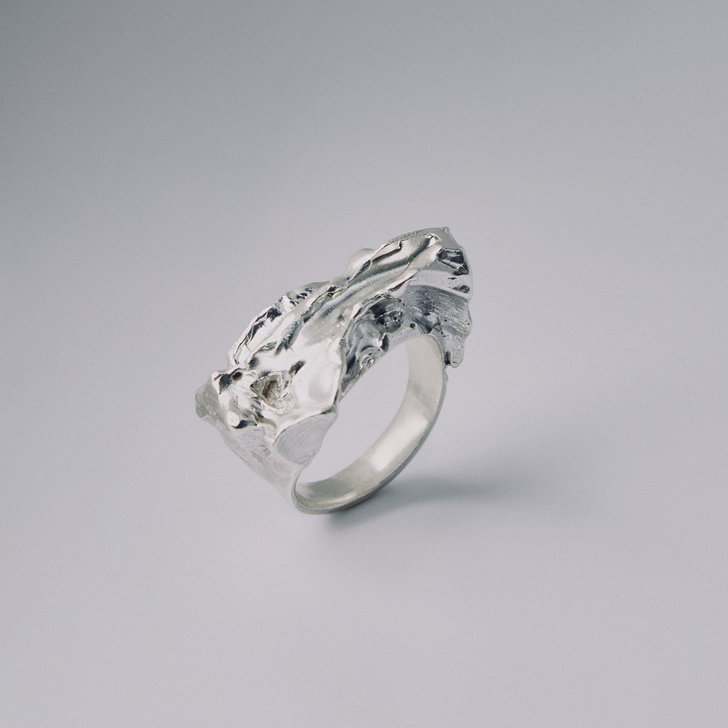 Silver ring with a textured design on a gray background