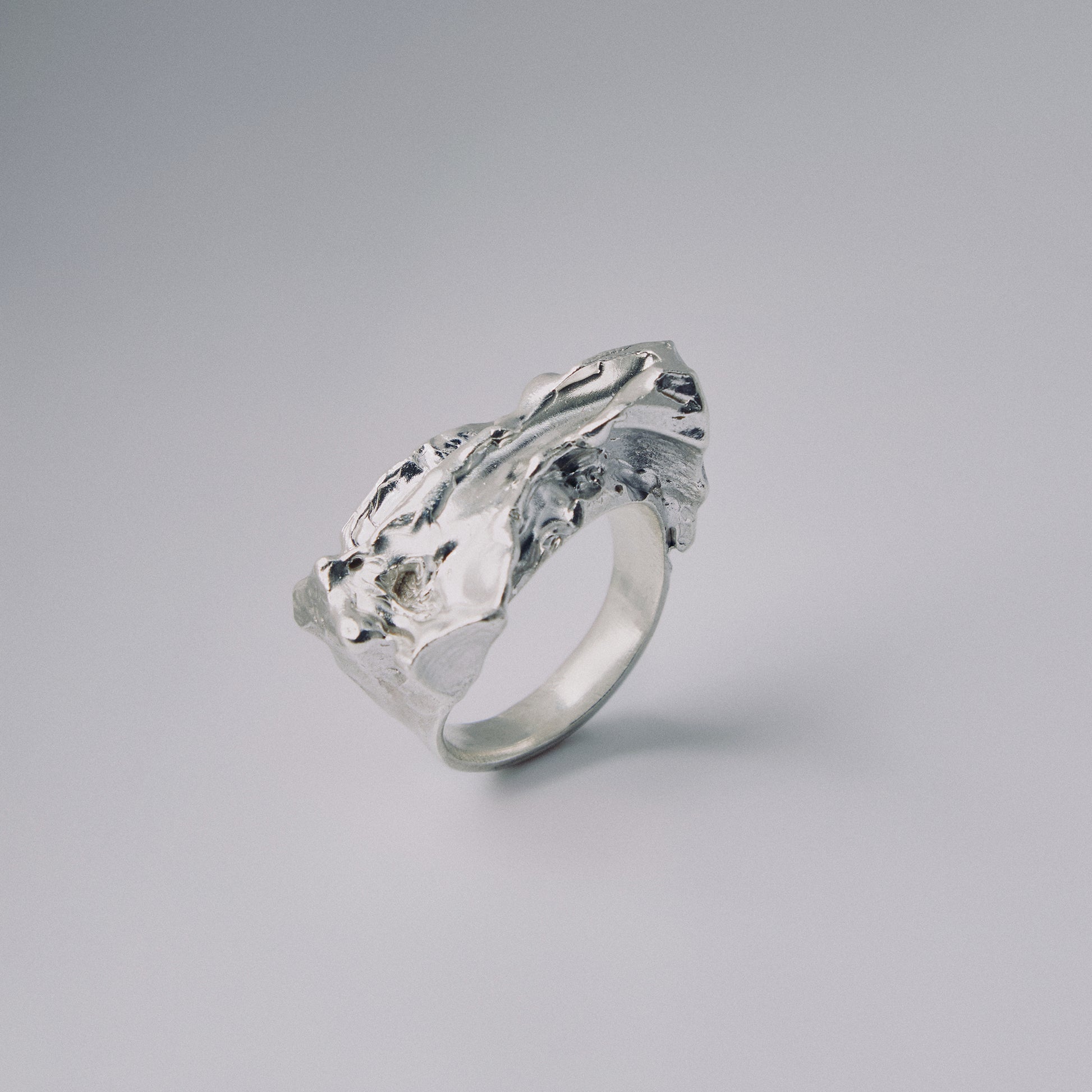 Silver ring with a textured design on a gray background