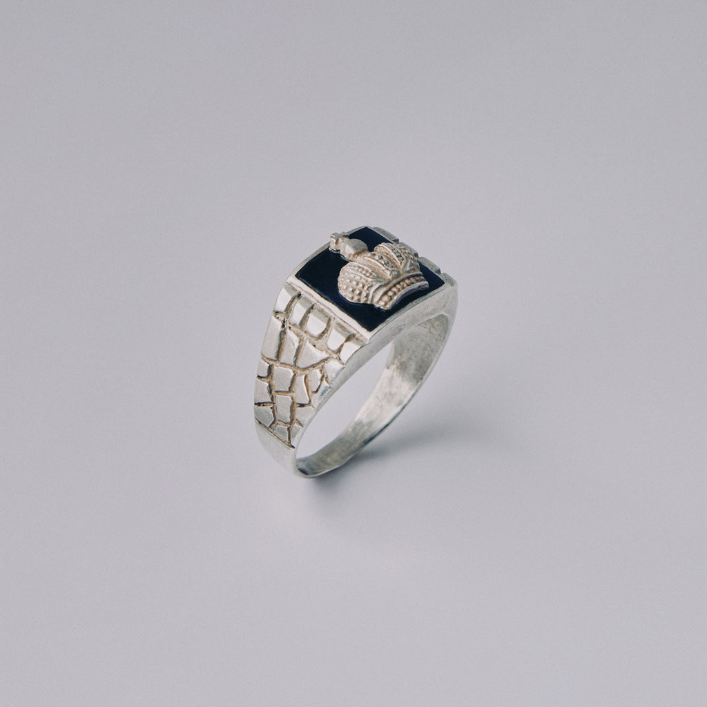 Silver crown ring with decorative design on a gray background