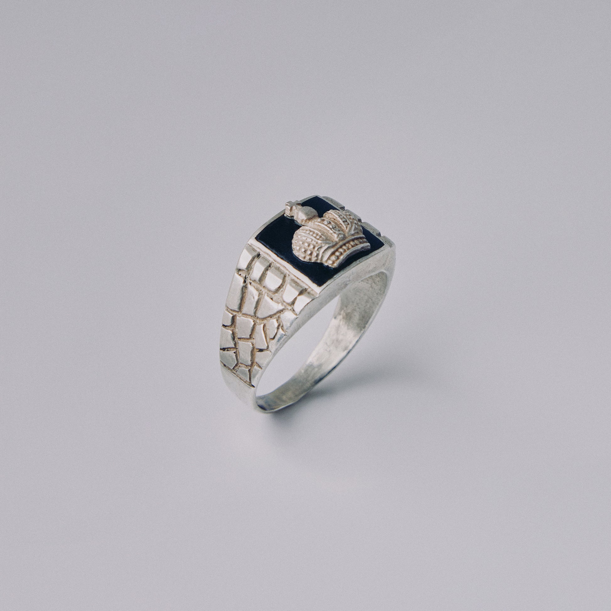 Silver crown ring with decorative design on a gray background