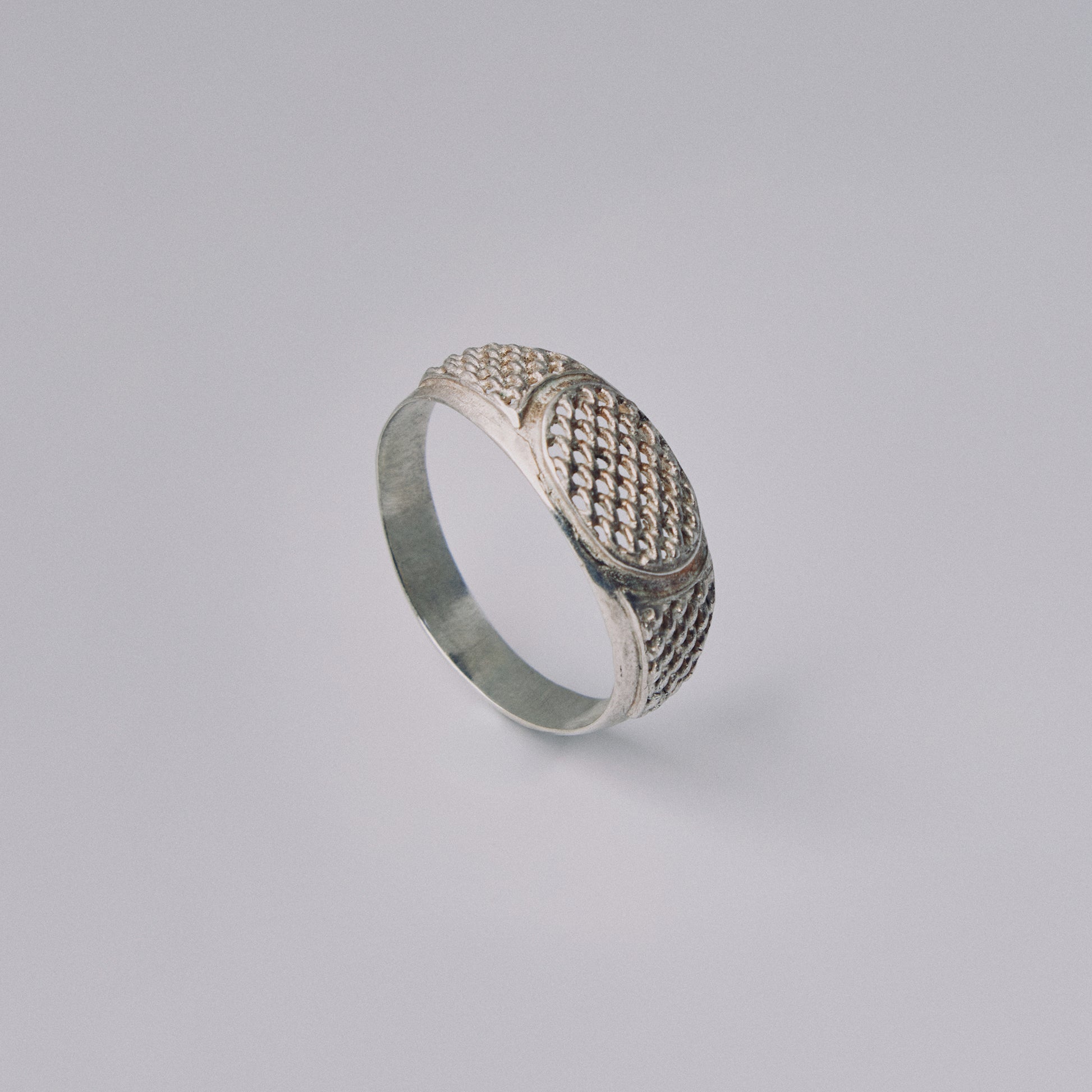 Silver ring with textured design on a light gray background