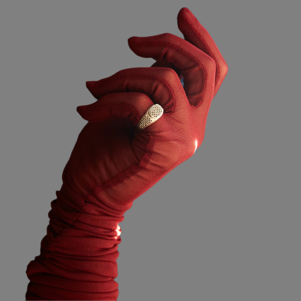 Red glove holding a gold ring against a blue curtain background