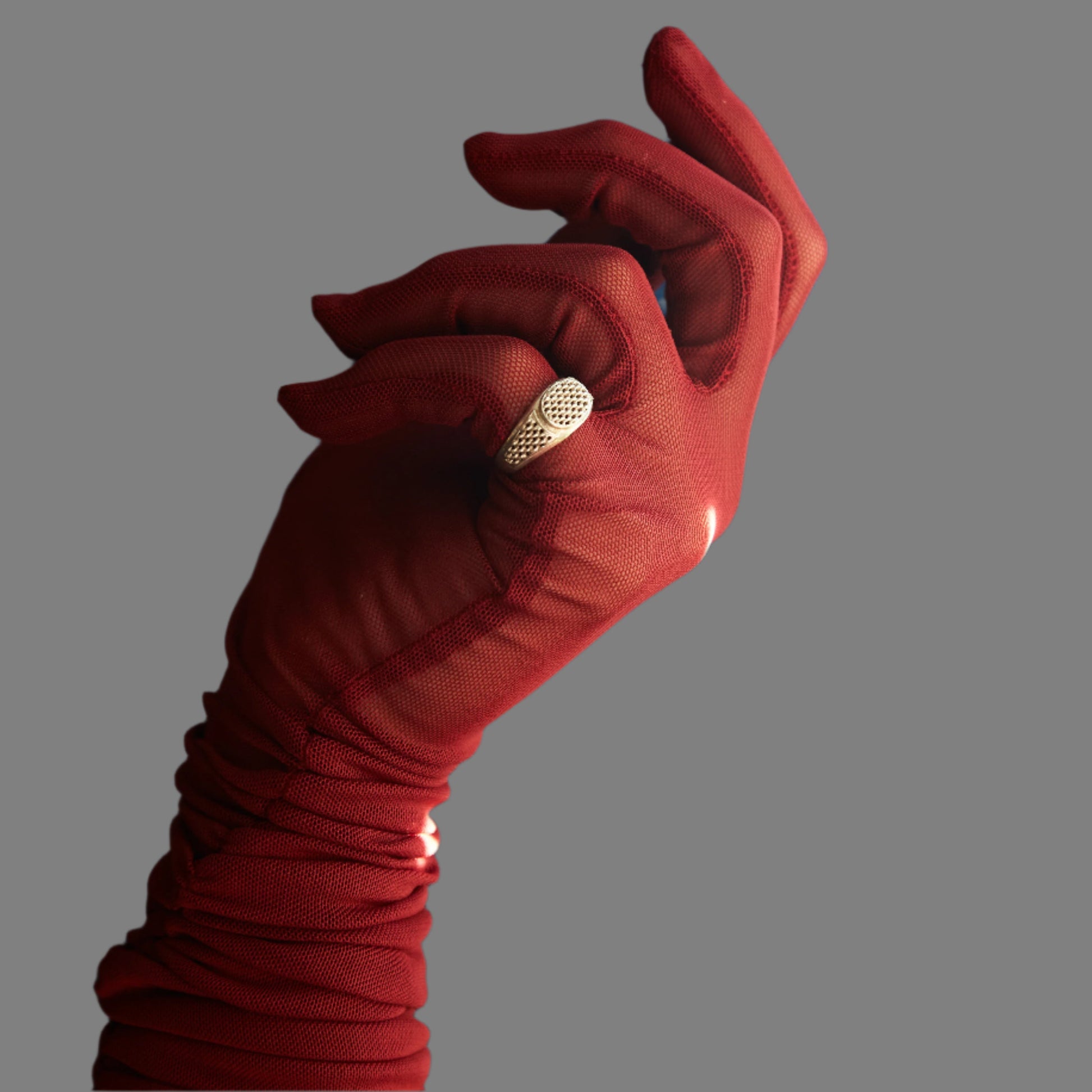 Red glove holding a gold ring against a blue curtain background