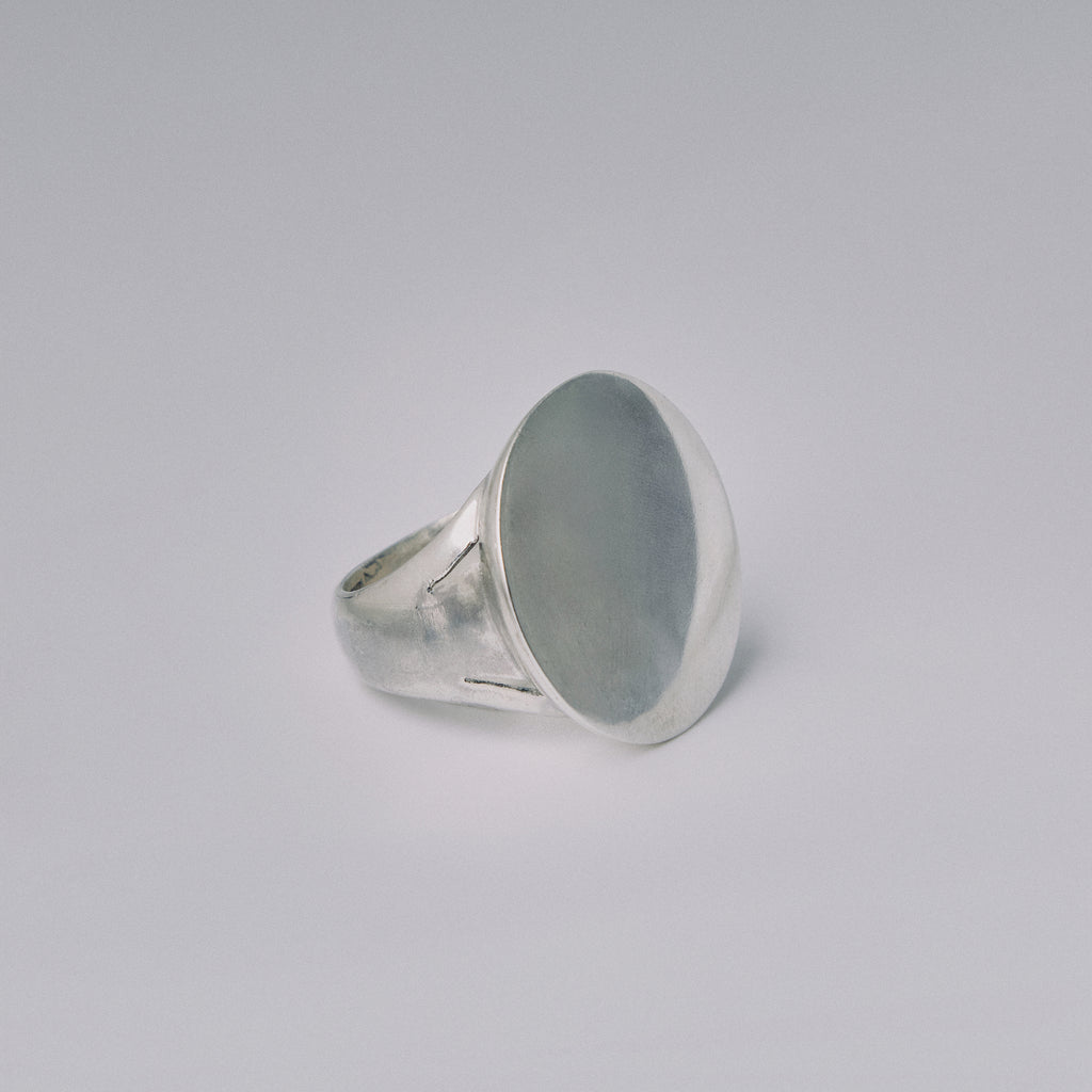 Silver ring with a large oval stone on a light gray background