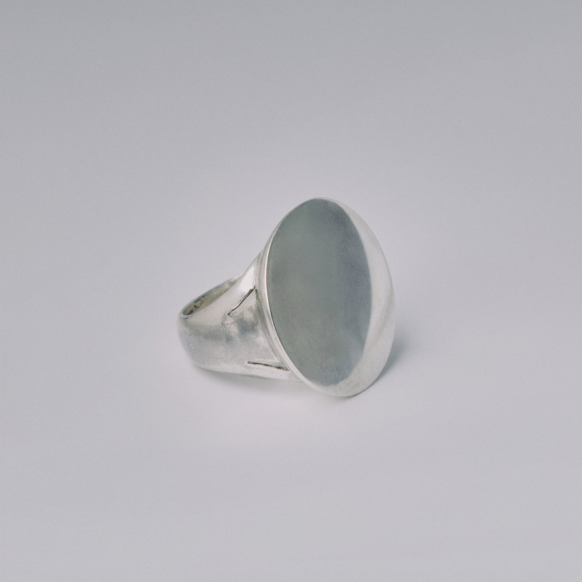 Silver ring with a large oval stone on a light gray background