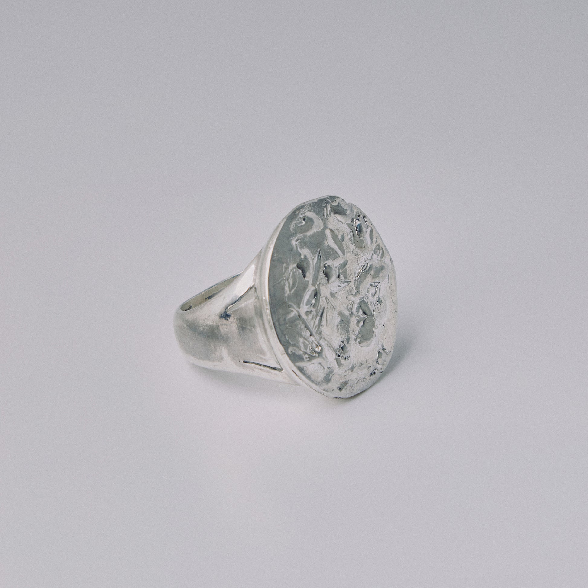 Silver ring with engraved design on a gray background