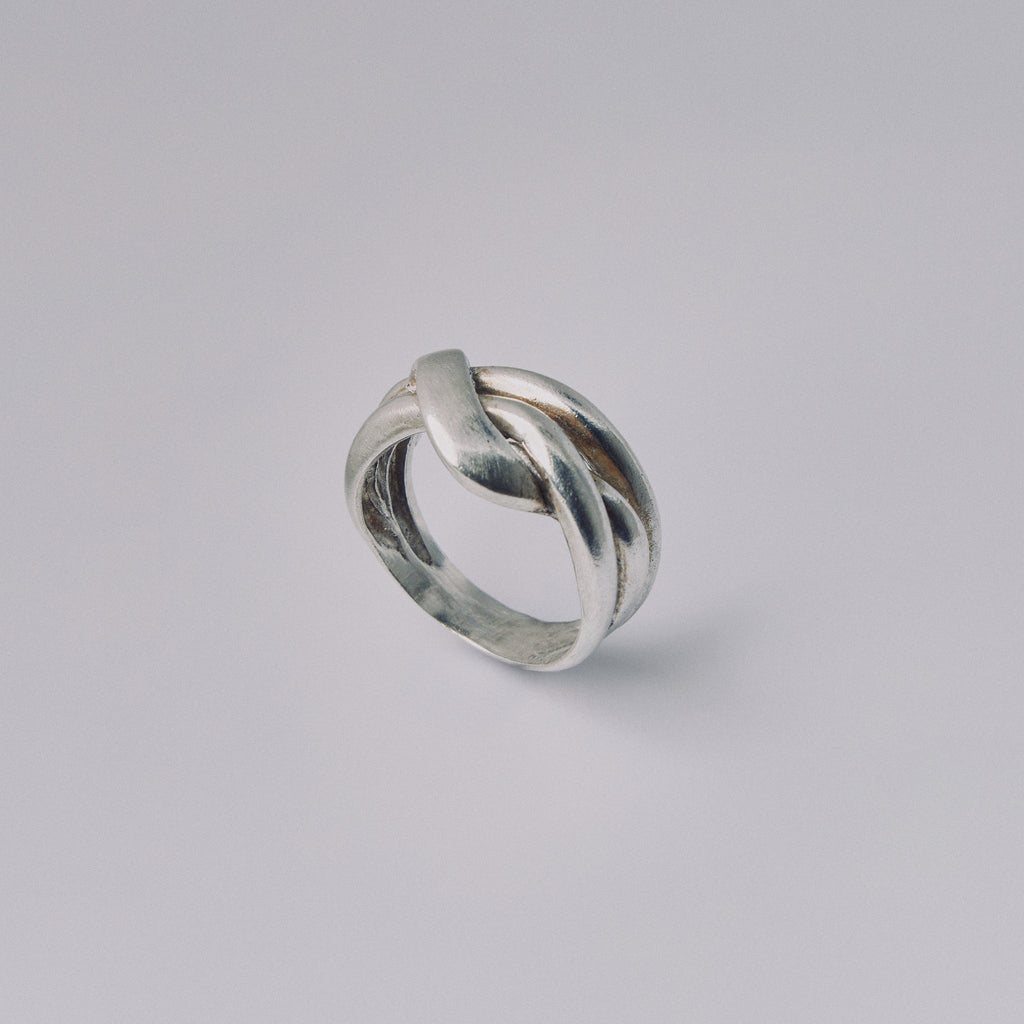 Silver ring with a twisted design on a gray background