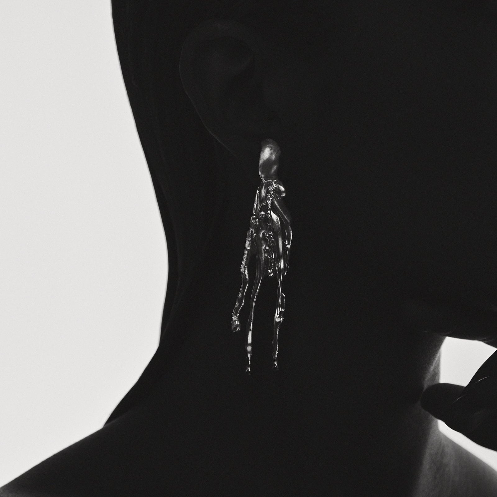 Silhouette of a person with a small, detailed figure on their neck against a light background