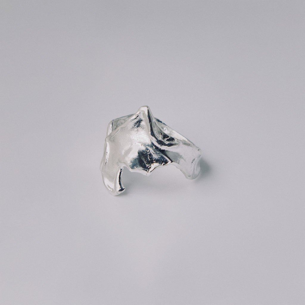 Silver ring with a textured design on a gray background