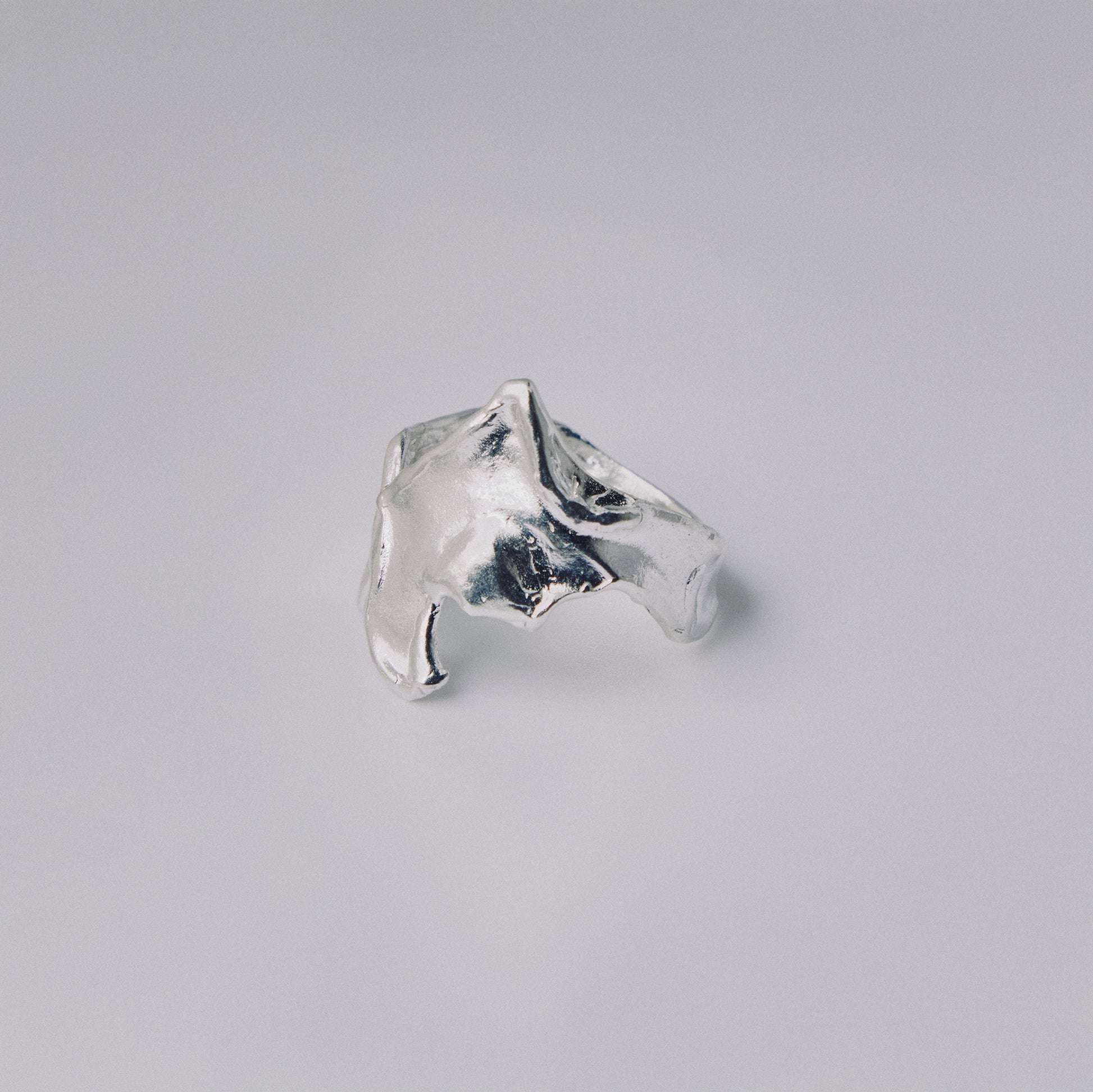 Silver ring with a textured design on a gray background