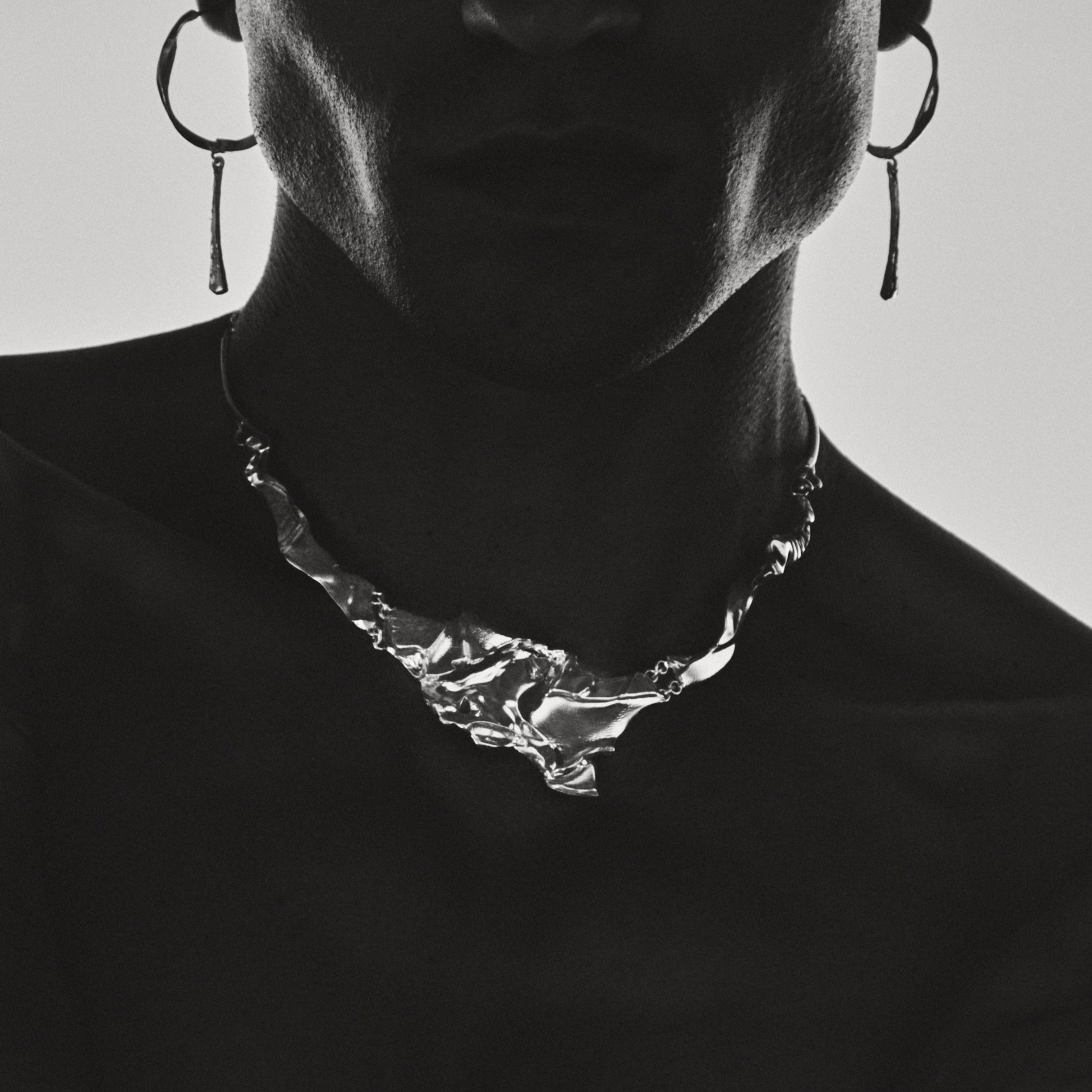 Silhouette of a person wearing a necklace with a minimal background