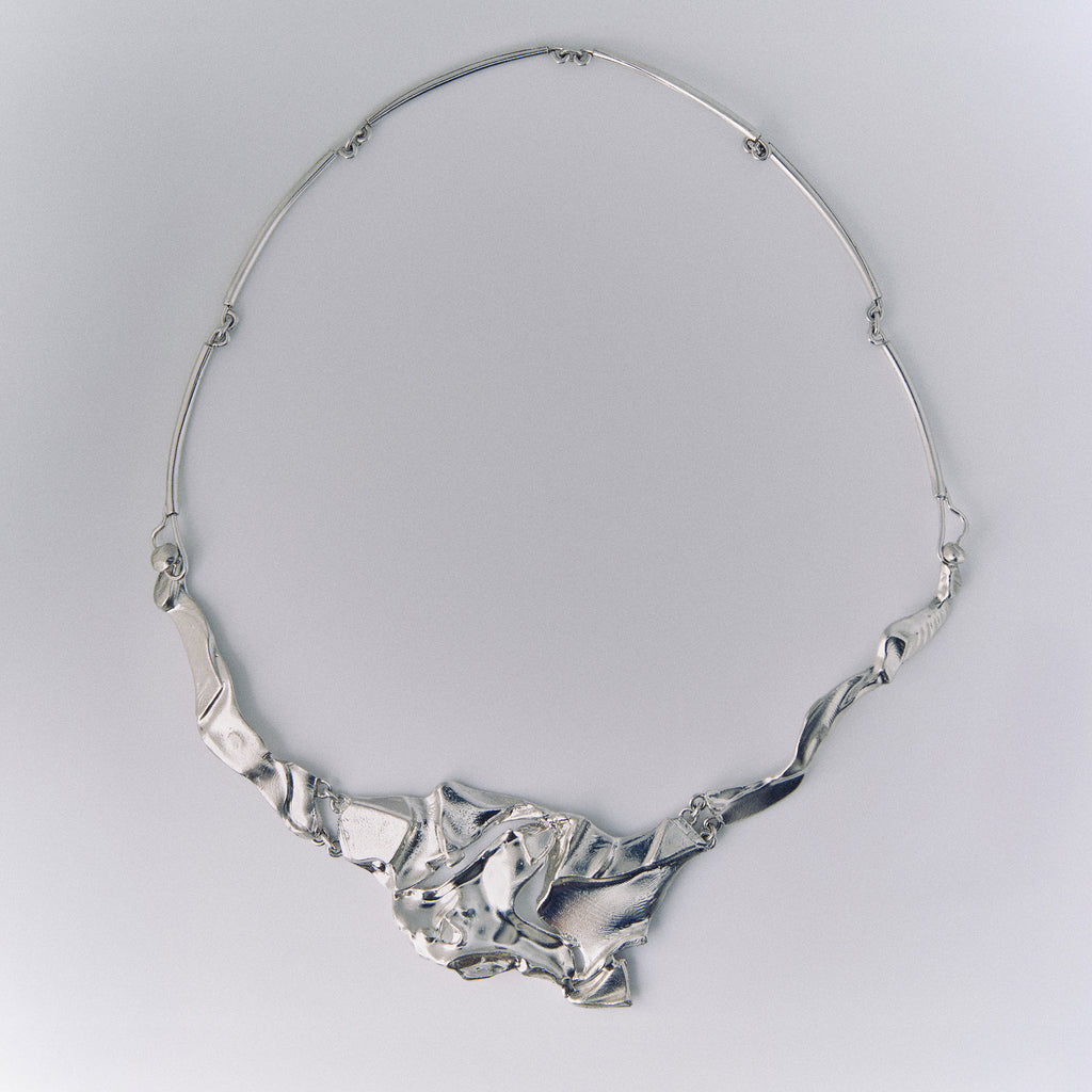 Silver necklace on a light gray background