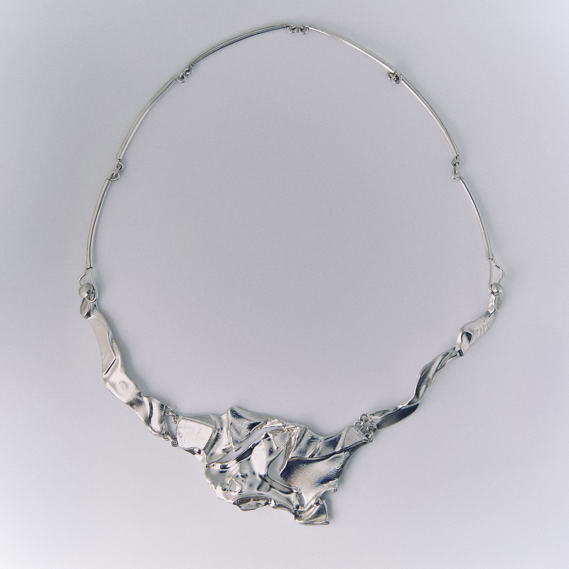 Silver necklace on a light gray background